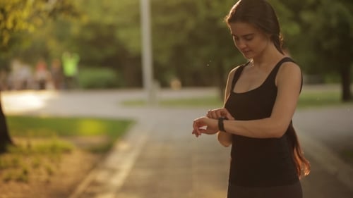 Young Woman Jogging With Smart Watch In Park