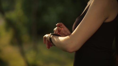 Young Woman Jogging With Smart Watch In Park