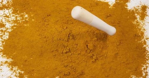 Currypulver fällt in einen Mörser und Stößel vor weißem Hintergrund, Zeitlupe 4K