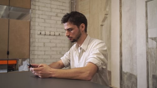 Thoughtful Young Man Using Phone in Modern Office