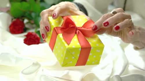 Senior Woman Holding Gift Box With Red Bow