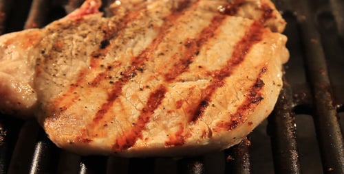 Pork Chop Sizzling on a Grill Close Up