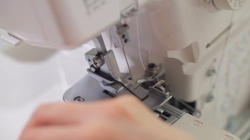 Woman's Hand Is Stretching Out Black Thread Through Overlock