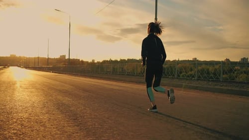 Woman Running on Road at Sunset