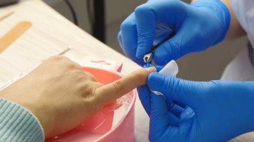 Manicurist Trimming Nails with Clippers in Salon