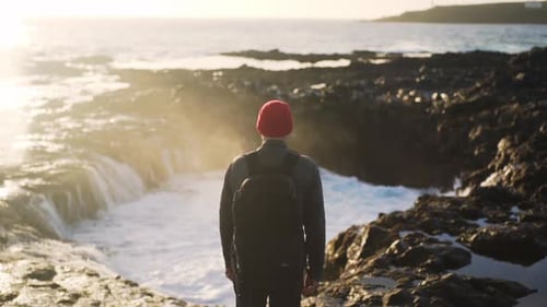 Man Looking At Sea Flow Into Rock Pool