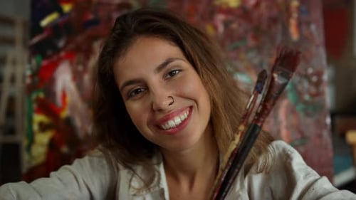 Smiling Artist in Art Studio with Paintbrushes