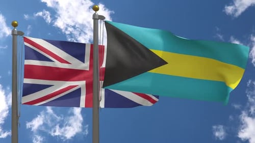 United Kingdom and Bahamas Flags Waving on Flagpoles Under Blue Sky