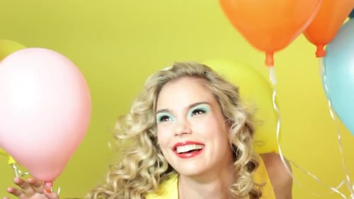 Woman Laughing with Colorful Balloons on Yellow Background