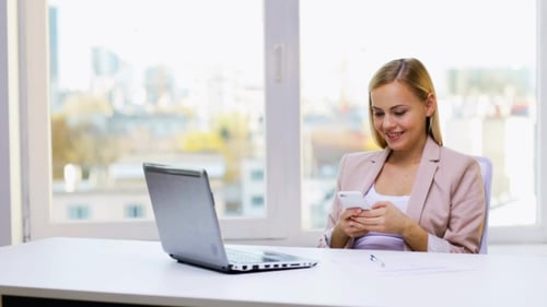 Woman Using Phone at Desk in Office