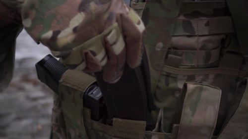 Un soldat met des munitions de fusil d'assaut dans les poches de son gilet de munitions
