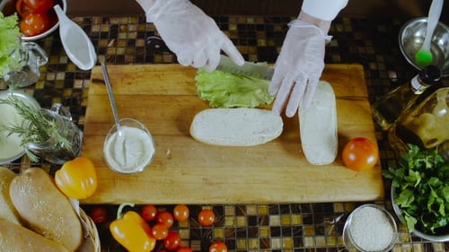 Person Prepares Sandwich on Wood Cutting Board