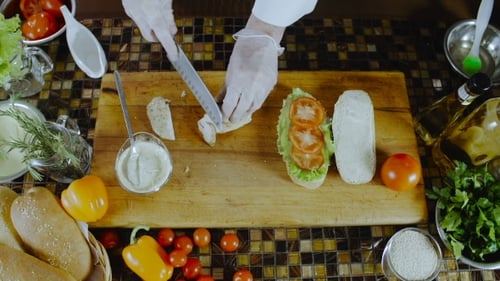 Chef Hands Making Chicken Sandwich on Cutting Board