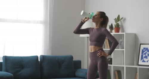 Woman Drinking Water After Exercise at Home