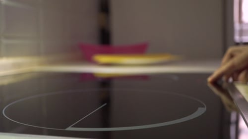 Finger Turns On Induction Cooktop in Kitchen