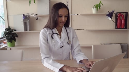 Female Doctor Working on Laptop in Bright Office