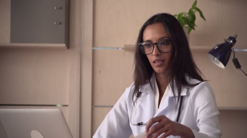 Professional Woman Doctor Tells and Hold Prescription in Hands
