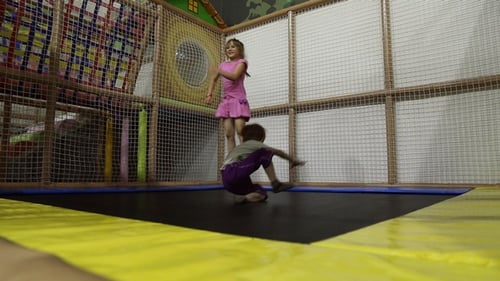 Una niña y un niño saltan en un trampolín