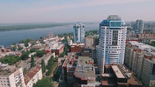 Aerocamera bewegt sich über die Stadt und fliegt in der Nähe moderner Wohnhäuser zum Fluss