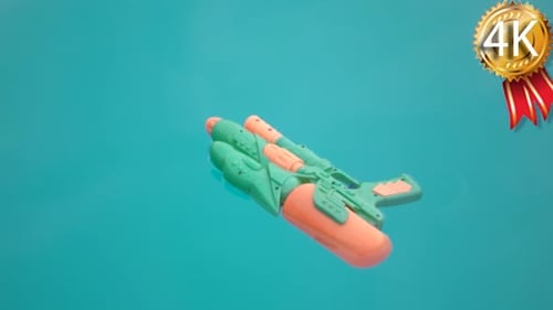Wasserpistole schwimmt in einem blauen Schwimmbadwasser