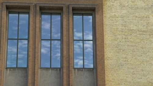 Brick Building Reflects Sky and Clouds