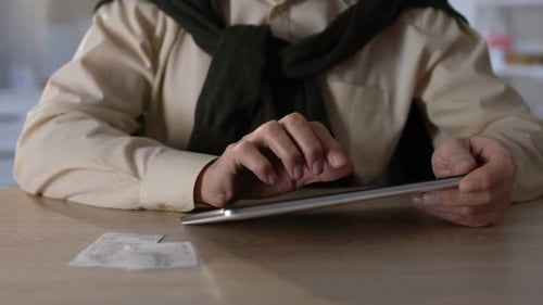 Person Using Tablet with Receipts on Desk