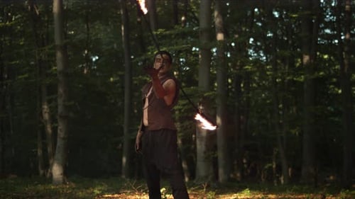 Performer Juggling Fiery Staff in Forest