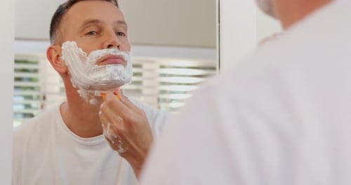 Homem raspando a barba com navalha no banheiro