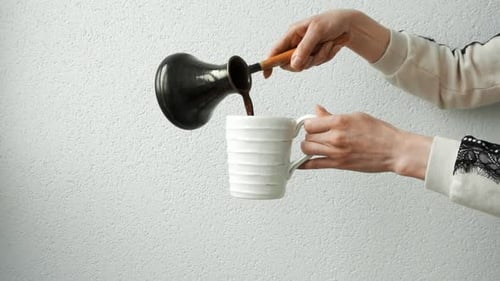 Coffee Pouring from Black Pot into Mug