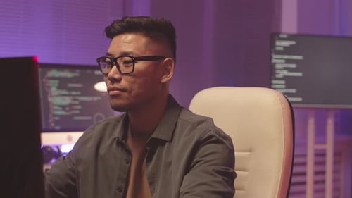 Young Adult Coding at Computer in Modern Office