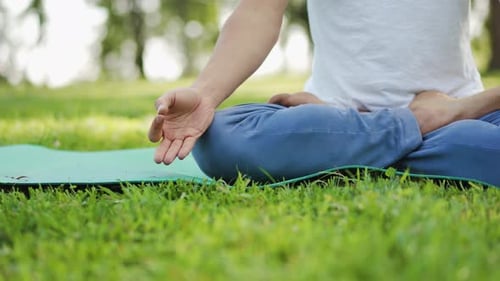 Young Adult Meditating Outdoors in Lotus Position