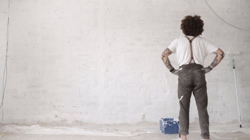 Young Adult Paints White Brick Wall