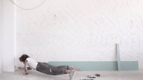 Fit Young Adult Doing Plank While Painting Wall