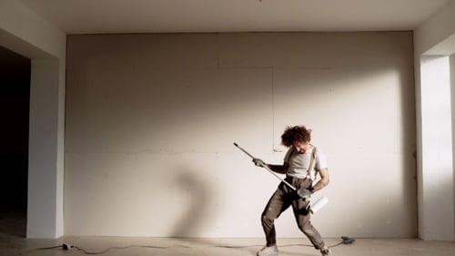 Man Dancing and Playing Paint Roller Like Guitar