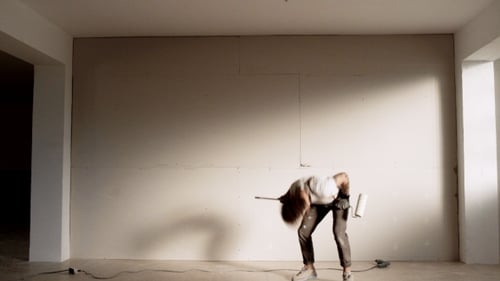 Man dancing with paint roller in empty room