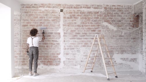 Adult Paints Brick Wall with Roller