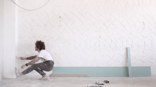 Young adult construction worker painting a wall