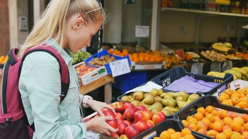 Mujer examinando frutas en el mercado callejero