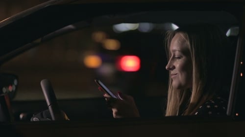 Woman Using Cellphone in Car at Night