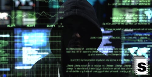 Hooded Person in Front of Multiple Computer Screens
