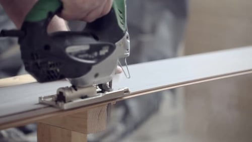Man Sawing Laminate with Jigsaw at Construction Site