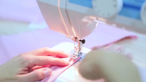 Woman Using Sewing Machine for Pink Garment
