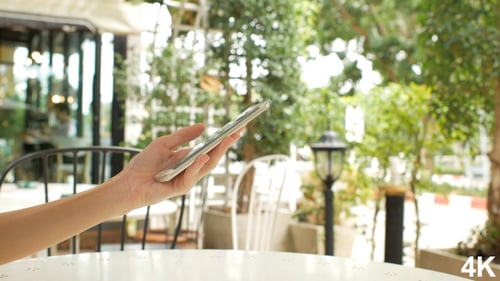 Hand Interacting With Phone At Outdoor Cafe