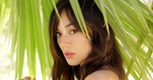 Young Woman Posing with Tropical Palm Leaves
