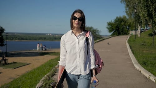 Young Beautiful Girl Walking At Park Holding a Skateboard