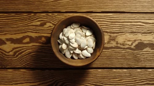Unpeeled pumpkin seeds appear in wooden cup and full this cup