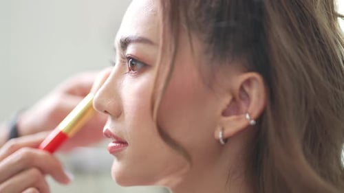 4K Asiatischer Visagist schminkt die weibliche Braut im weißen Hochzeitskleid.