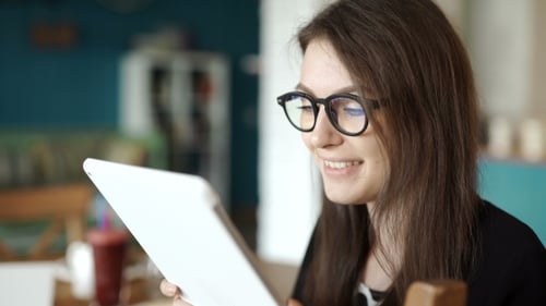 Woman Sits At a Table At a Restaurant. Carried a Tablet With Access To Internet