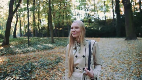 Beautiful Young Blonde Girl Walking in the Park in Autumn