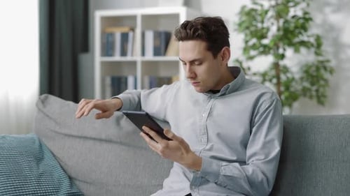 Man Relaxing on Couch Using Tablet at Home